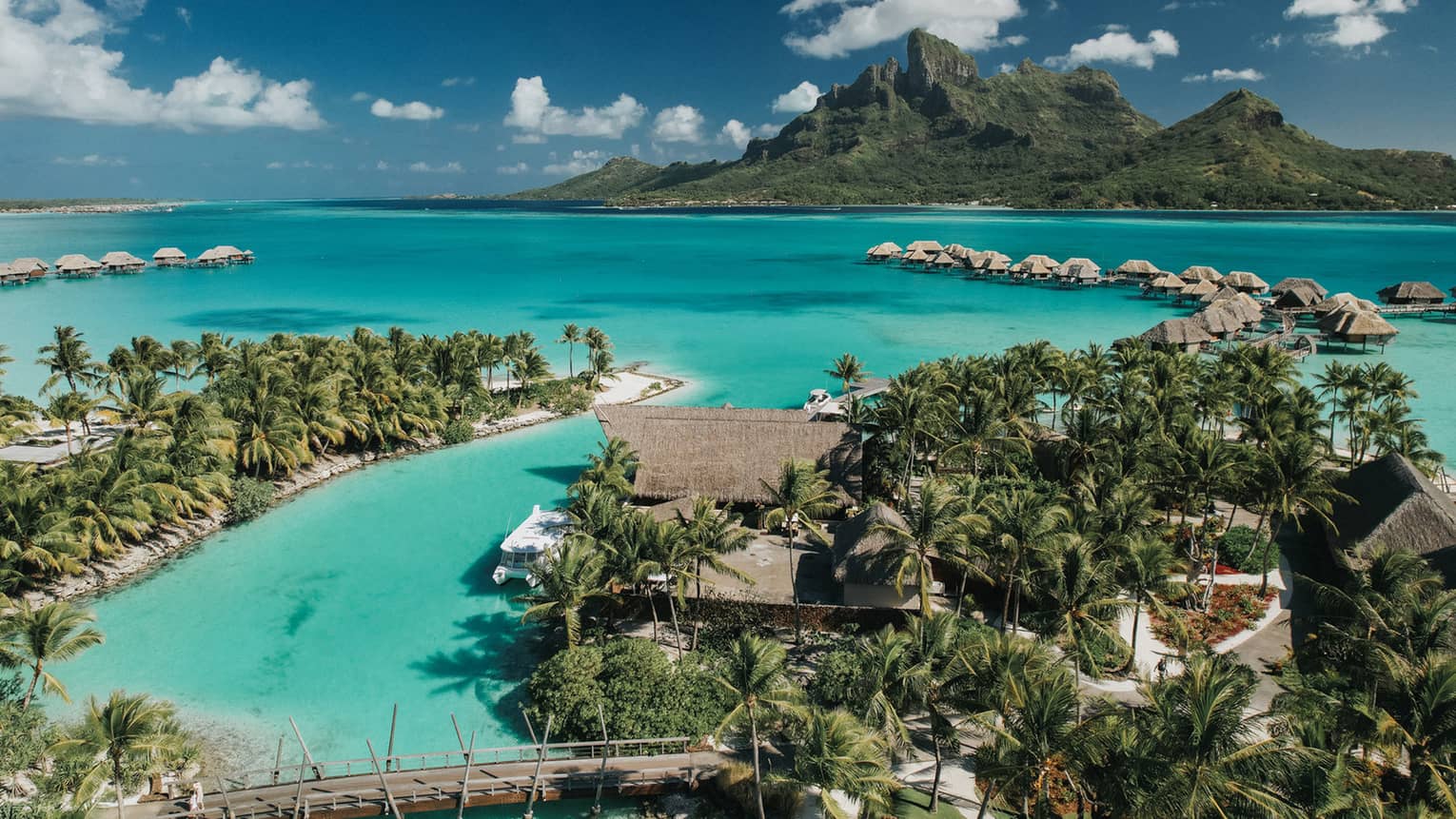 Overwater villas on a turquoise Bora Bora lagoon with Mount Otemanu in the background.